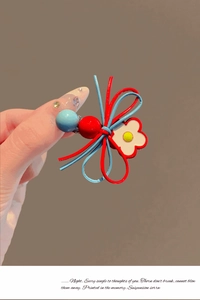 Détail de la pince à cheveux noeud en cuir avec fleur colorée et perles décoratives