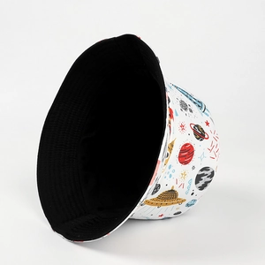 Detailed view of reversible bucket hat showing black side and white space cartoon pattern