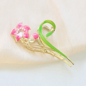 Detail of golden metal hair claw with pink gardenia flowers and pearl accents