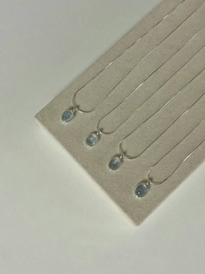 Detailed view of silver necklaces with oval aquamarine pendants on a velvet display