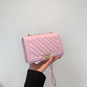 Detailed close-up of pink V-stitch crossbody bag with gold chain strap and turn-lock