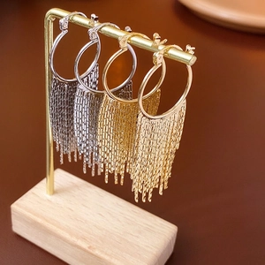 Élégantes créoles plaquées or et argent avec de longs pompons en métal sur un présentoir