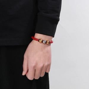 Detail of red braided leather bracelet with gold and silver beads on a wrist