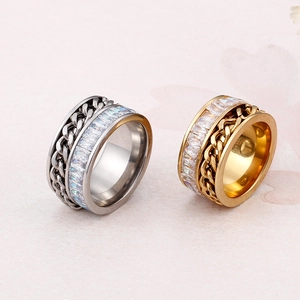 Gold and silver Cuban chain rings with rectangular zircon stones on a pink background