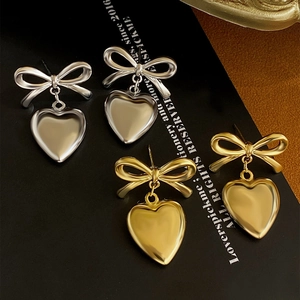 Macro shot of silver and gold bowknot heart pendants on elegant black brand cards