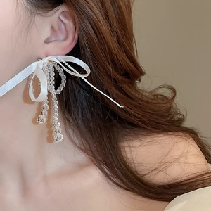 Detail shot of white ribbon bow earrings with faceted crystal beads on model