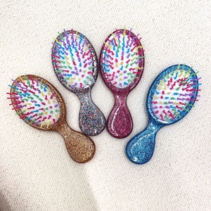 Set of four mini glitter hairbrushes with colorful bristles on a knit background