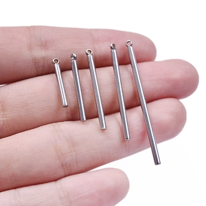 Close-up of five silver stainless steel bar pendants in varying lengths held by hand