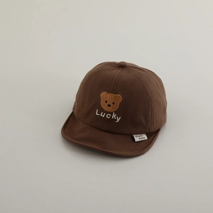 Close-up of brown cotton baby cap with embroidered bear and Lucky text detail
