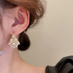 Detail shot of vintage gold-plated pearl drop earrings worn by a model in a side view