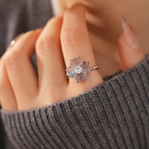 Gros plan d'une bague trèfle aux pétales bleus et zircon central sur un mannequin