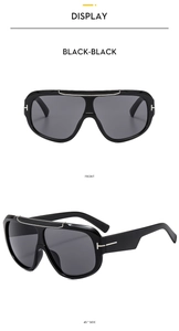 Close-up of black oversize sports sunglasses featuring signature metallic T-shaped temple hinge