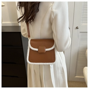 Détail du sac bandoulière en cuir marron avec bordure en laine de mouton sur un mannequin