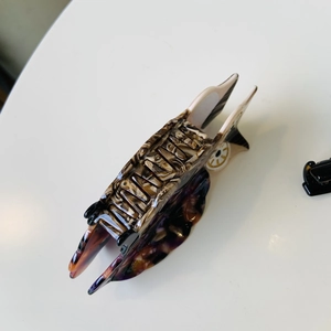 Detail shot of acetate hair claw with vintage marble texture in brown and purple tones