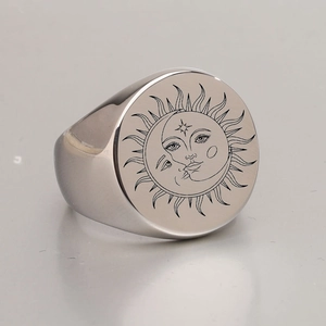 Close-up of a silver stainless steel signet ring with engraved sun and moon patterns