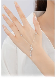 Close-up of a silver moon and star necklace with zircons worn on a female neck