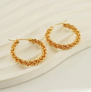Macro shot of gold twisted rope hoop earrings with a textured woven metal finish