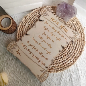 Laser engraved scroll-shaped wooden Mother's Day plaque on a rustic woven mat decoration