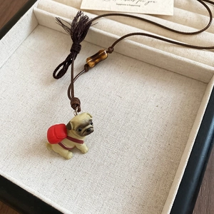Close-up of pug pendant with red backpack on brown wax rope with wood bead and tassel