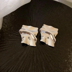 Macro shot of silver irregular wrinkled earrings with a shiny metallic textured finish