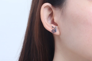 Nahaufnahme der silbernen Schnecken-Ohrstecker am Ohr eines Models im natürlichen Stil