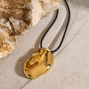 Collana minimalista a goccia d'oro organico su sfondo in pietra naturale materica