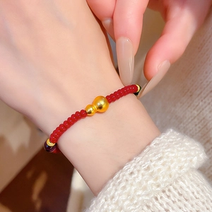 Gros plan d'un bracelet en perles rouges avec un pendentif gourde dorée sur tricot