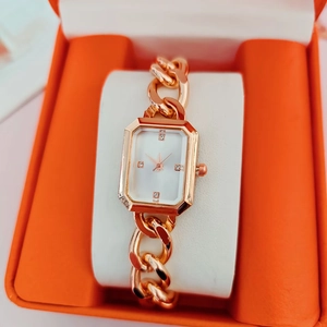 Elegante reloj cuadrado dorado con esfera blanca sobre cojín suave en caja de regalo