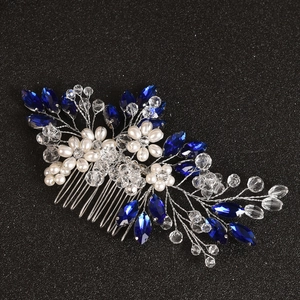 Detail of handmade bridal hair comb with blue gems, pearls, and crystals on black texture