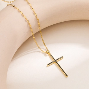 Detailed macro view of a gold cross pendant necklace with black cubic zirconia stones