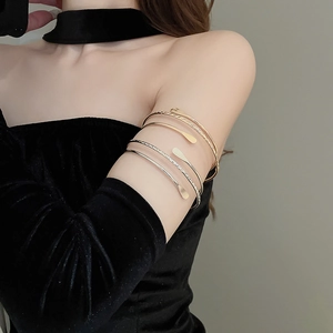 Detailed close-up of multilayer gold and silver arm cuffs on black velvet sleeve