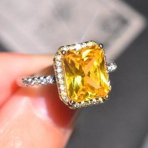 Macro view of a rectangular yellow gemstone ring with a halo of white pavé diamonds