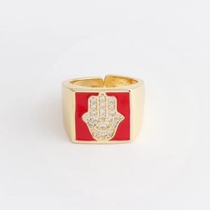 Detail of gold-plated Hamsa Hand ring with red enamel background and white zircon stones