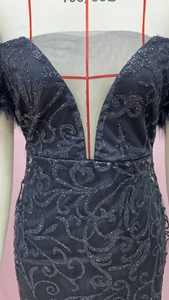 Detail eines schwarzen Pailletten-Abendkleides mit Stickerei und tiefem V-Ausschnitt