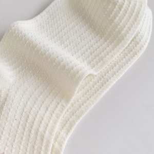 Detailed macro shot of white waffle-knit fabric and breathable mesh texture of socks