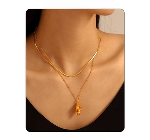 Nahaufnahme einer zweilagigen 18k Goldkette mit Seeschnecken-Anhänger an einem Model