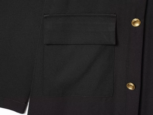 Détail de robe midi noire avec poche à rabat et boutons métalliques dorés à relief