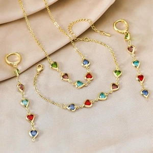 Parure bijoux cœur multicolore avec collier doré, bracelet et boucles sur du satin