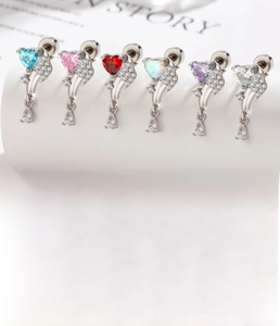 Macro detail of heart-shaped wing earrings with zircon inlays and screw back specifications