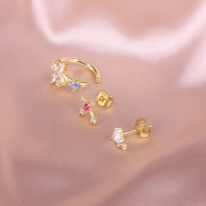 Close-up of S925 silver flower ear cuff and star studs with colorful zircons on pink silk