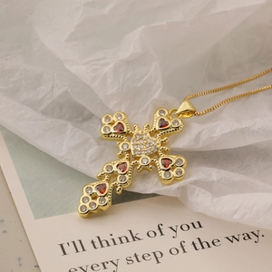 Gold-plated cross necklace with clear and red zircon stones on a decorative card