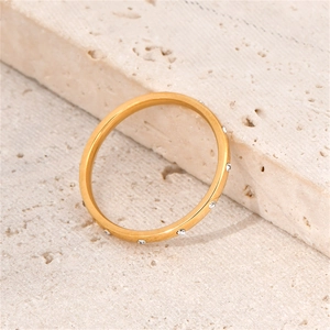 Close-up of minimalist gold titanium ring with zircon droplets on stone surface