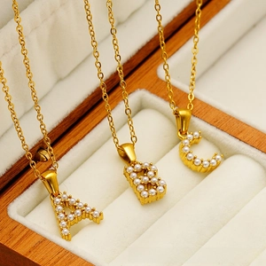 Close-up of gold-plated titanium steel necklaces with pearl-inlaid A, B, C pendants