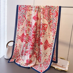 Elegant silk-like scarf with vintage red paisley prints and blue borders on display