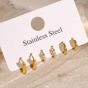 Three pairs of gold stainless steel hoop earrings including plain and crystal pavé designs