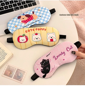 Three assorted cute cartoon sleep masks with elastic straps on a cozy home desk