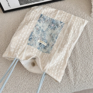 Detail of cream lace tote bag with blue floral patch and magnetic closure
