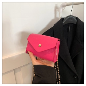 Close-up of pink faux leather bag with crocodile pattern and golden metal chain strap