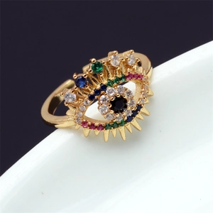 Détail macro d'une bague en forme d'œil avec zircons colorés sur support blanc