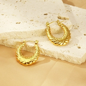 Detailed view of 18k gold plated U-shaped earrings with textured wavy finish on stone